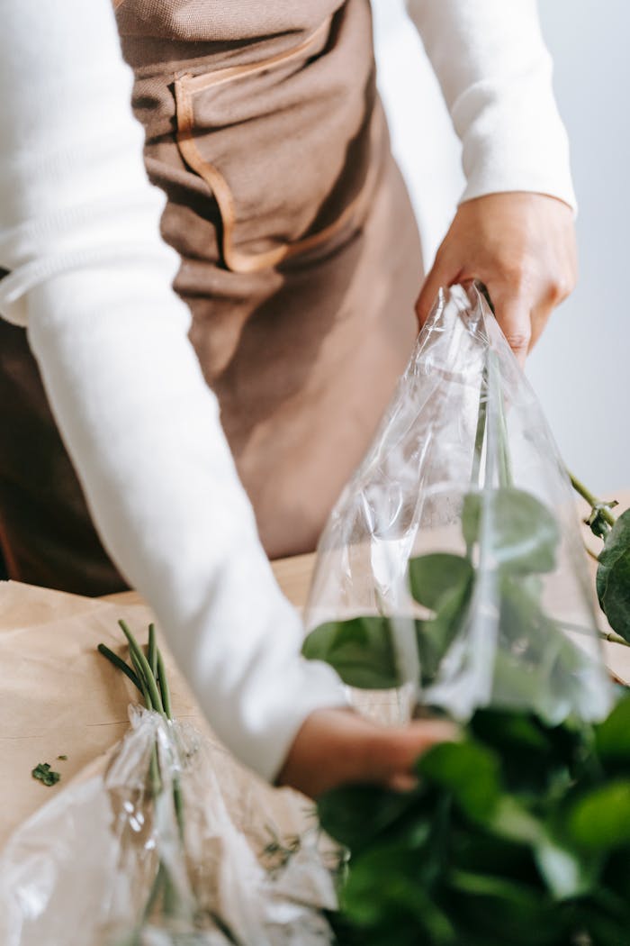Florist wrapping fresh bouquet in plastic at a market, highlighting floral business ambiance.